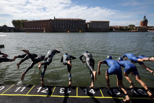 Triathletes dive into the Garonne river as they compete in the men's Supertri triathlon in Toulouse, south-western France, on October 6, 2024. (Photo by Valentine Chapuis/AFP Photo)