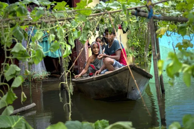 A flood affected family leaves their marooned house on boat to a safer place from Tarabari village, west of Gauhati, in the northeastern Indian state of Assam, Monday, June 20, 2022. Authorities in India and Bangladesh are struggling to deliver food and drinking water to hundreds of thousands of people evacuated from their homes in days of flooding that have submerged wide swaths of the countries. The floods triggered by monsoon rains have killed more than a dozen people, marooned millions and flooded millions of houses. (Photo by Anupam Nath/AP Photo)