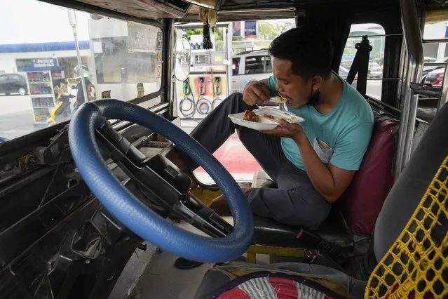 Passenger jeepney driver, Jet Marty dela Cruz, eats lunch inside his vehicle to save fuel instead of heading home as he takes a break at a gasoline station in Quezon City, Philippines on Monday, June 20, 2022. Around the world, drivers are looking at numbers on the gas pump and rethinking their habits and finances. (Photo by Aaron Favila/AP Photo)