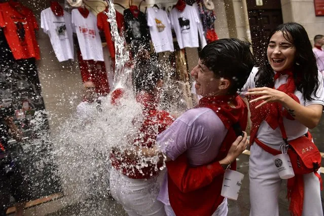 Water is thrown on revelers celebrating the launch of the “Chupinazo” rocket, to mark the official opening of the 2022 San Fermin fiestas in Pamplona, Spain, Wednesday, July 6, 2022. (Photo by Alvaro Barrientos/AP Photo)