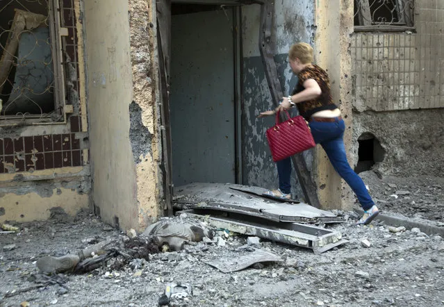 A woman rushes into her house past the body of a community service worker who was killed during the shelling at a residential apartment house in Donetsk, eastern Ukraine Tuesday, July 29, 2014. Local residents said it was a shelling from direction of Ukrainian army's positions. (Photo by Dmitry Lovetsky/AP Photo)