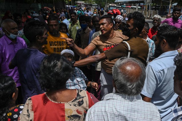 People quarrel as they wait in a queue to collect Liquefied Petroleum Gas (LPG) cylinders at a distribution point in Colombo on July 12, 2022. (Photo by Arun Sankar/AFP Photo)