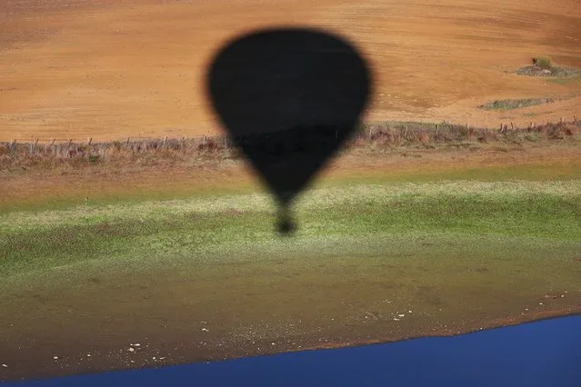 A balloon casts a shadow on the ground as it flies in the air during the 24th International Hot Air Balloon Festival near Alter do Chao, northern Alentejo, Portugal, 09 November 2021. The ballooning event takes place at various locations in Portugal until the 14 November 2021. (Photo by Nuno Veiga/EPA/EFE)