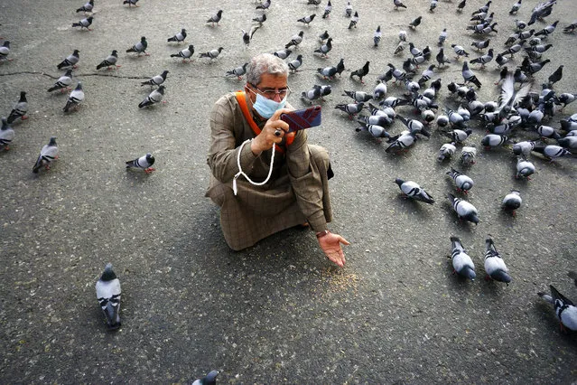 A Muslim pilgrim feeds pigeons outside the Grand Mosque, in the Muslim holy city of Mecca, Saudi Arabia, Thursday, March 5, 2020. Saudi Arabia's Deputy Health Minister Abdel-Fattah Mashat was quoted on the state-linked news site Al-Yaum saying that groups of visitors to Mecca from inside the country would now also be barred from performing the pilgrimage, known as the umrah. (Photo by Amr Nabil/AP Photo)