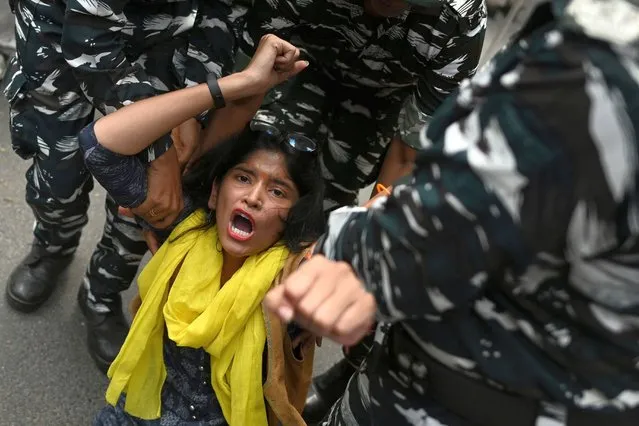 Members of security personnel detain an activist of India's Aam Aadmi Party (AAP) near the Bharatiya Janata Party (BJP) headquarters during a protest in New Delhi on July 27, 2022, after at least 30 people allegedly died due to consumption of spurious liquor in Gujarat state. (Photo by Sajjad Hussain/AFP Photo)