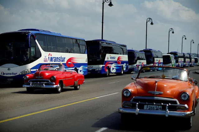 Vintage cars pass by a fleet of Chinese-made Yutong buses parked at the sea front Malecon in Havana, Cuba, February 10, 2017. (Photo by Alexandre Meneghini/Reuters)