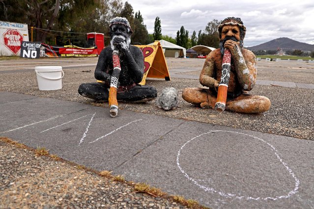 Two statues of Indigenous Australians with didgeridoos sit in front of the Aboriginal Tent Embassy located outside the old Parliament House in Canberra on October 15, 2023. (Photo by David Gray/AFP Photo)
