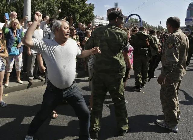 A man throws an egg at captured Ukrainian army prisoners as they're escorted by Pro-Russian rebels in a central square in Donetsk, eastern Ukraine, Sunday, August 24, 2014. (Photo by Sergei Grits/AP Photo)