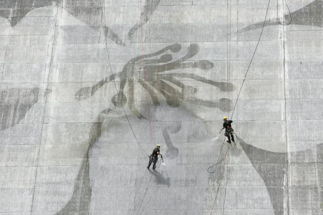 Two men clean the Matsudagawa Dam in Japan. (Photo by Caters News Agency)