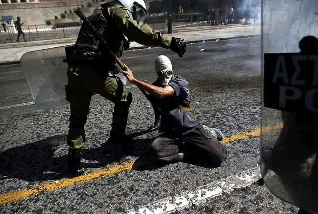 A demonstrator scuffles with a police officer during clashes in Athens, Greece, on September 26, 2012. Widespread protests erupted across Greece after trade unions called a nationwide strike to contest new salary and pension cuts being discussed by the government. (Photo by Angelos Tzortzinis/The New York Times)