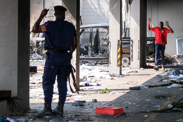 A Congolese police officer stops protesters at the building housing the Rwandan embassy, looted by protesters, in Kinshasa, Democratic Republic of Congo on January 28, 2025. (Photo by Justin Makangara/Reuters)