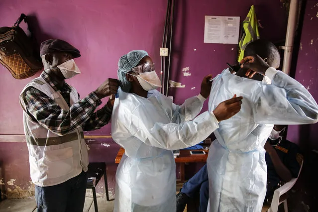 Medical staff aid each other to put on protective equipment as a precaution before dealing with patients with non-coronavirus related issues at the Medecins Sans Frontieres (Doctors without Borders) clinic in the Mathare slum, or informal settlement, of Nairobi, Kenya Thursday, May 28, 2020. According to MSF, measures being taken to curb the spread of the coronavirus such as a nightly curfew and transport restrictions, shortages of protective equipment, and the risk of contamination, are causing disruption to the provision of general health services in the low-income neighborhood. Some of these include the closure of private clinics and an unwillingness by others to admit patients with respiratory issues caused by tuberculosis, asthma or pneumonia. (Photo by Brian Inganga/AP Photo)
