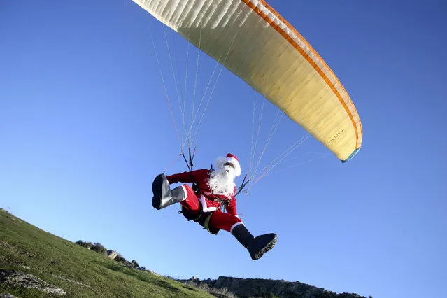 A man clothed as Santa Claus paraglides near Ajaccio, on the French Mediterranean island of Corsica, on December 19, 2021. (Photo by Pascal Pochard-Casabianca/AFP Photo)