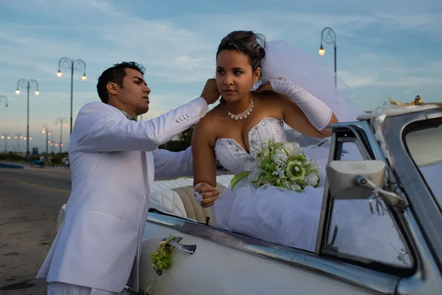 As the sun sets on the Malecon in Havana on Friday January 23, 2015, Nelson Boo Gonzalez, 26, left, helps his wife of only hours, Yunaisis Conconon Isaac, 25, with her necklace. (Photo by Sarah L. Voisin/The Washington Post)