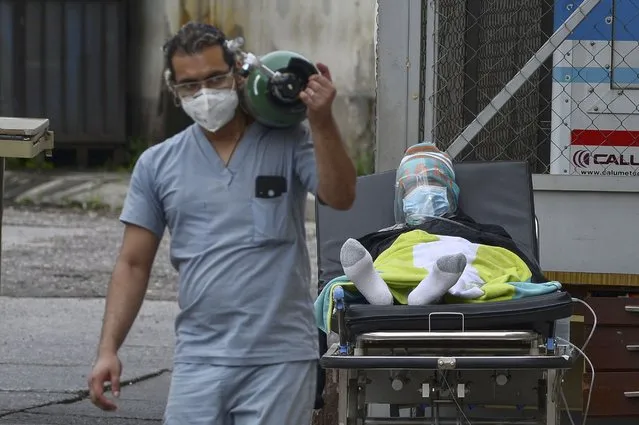 A doctor carries an oxygen tank after disconnecting a man infected with COVID-19 from it at a field hospital set up in the yard of the School Hospital in Tegucigalpa on June 17, 2020. The authorities of the main hospital of the Honduran capital were forced to set up four tents to assist coronavirus patients since its rooms were overcrowded. The country has so far registered 9,658 contagions and 478 deaths from COVID-19. (Photo by Orlando Sierra/AFP Photo)