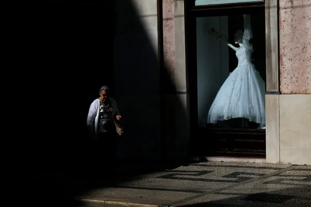 A woman walks past a shop displaying a bridal dress in the Baixa neighborhood of Lisbon, Portugal on Thursday, May 7, 2015. (Photo by Francisco Seco/AP Photo)