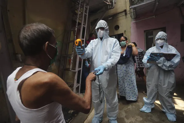 A doctor checks the temperature of a man during a free medical camp in Dharavi, one of Asia's largest slums in Mumbai, India, Saturday, June 20, 2020. India is the fourth hardest-hit country by the COVID-19 pandemic in the world after the U.S., Russia and Brazil. (Photo by Rafiq Maqbool/AP Photo)