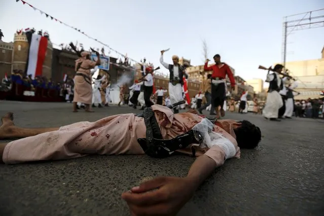 A Houthi follower with fake blood on his clothes lies on the ground to represent a victim as others perform a war dance during a ceremony marking the first anniversary of the Houthi movement's takeover of Yemen's capital Sanaa September 21, 2015. (Photo by Khaled Abdullah/Reuters)