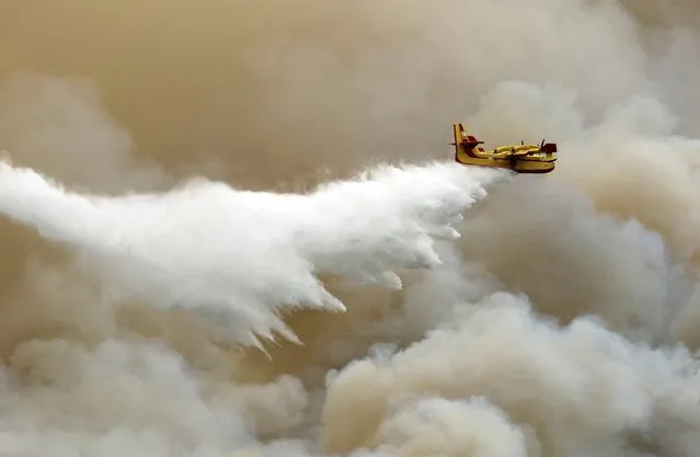 A firefighting aircraft drops water over a forest fire on the island of Thassos, northern Greece, 11 September 2016. A wildfire that broke out on the northern Aegean island of Thassos continued to rage for a second day on 11 September with authorities making every effort to get the various fronts under control before nightfall. (Photo by Haris Iordanidis/EPA)