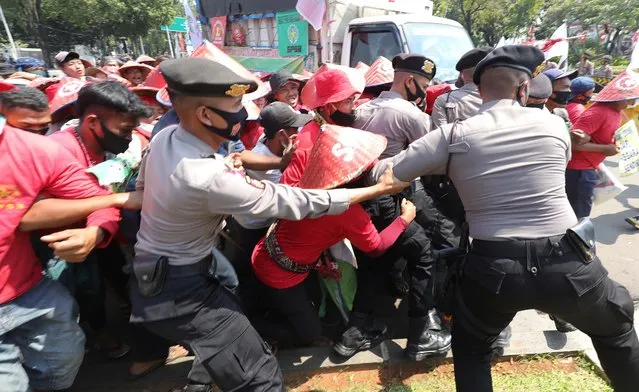 Protesters seen breaking through the barricades during a demonstration outside the Presidential Palace in Jakarta, Indonesia on August 26, 2020. The protesters, mainly farmers arrived in  Jakarta earlier this month. They marched 1,800km from Medan to Jakarta in 45 days to protest against evictions by Indonesian state-owned enterprises, PT Perkebunan Nusantara II or PTPN II.
(Photo ny Jefta Images/Barcroft Media via Getty Images)