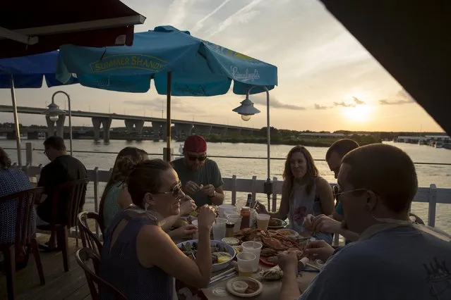 Diners eat blue crabs as the sun sets over the Kent Narrows at Harris Crab House in Grasonville, Maryland September 5, 2015. (Photo by Jonathan Ernst/Reuters)