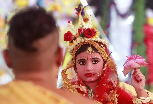A Hindu (L) priest performs traditional worship of Nilanjana Chakraborty, a five-year old girl dressed as a Kumari, during the religious festival of Durga Puja in Agartala, India, October 21, 2015. (Photo by Jayanta Dey/Reuters)