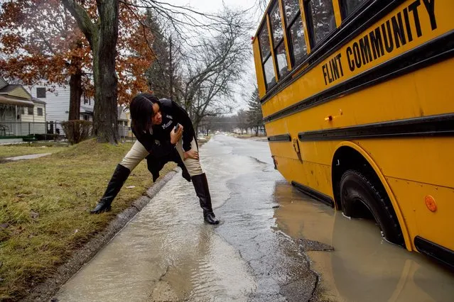 Ketara Sealey, 17, takes a photo of the school bus' tire on Tuesday, February 20, 2018, in Flint, Mich. The bus became stuck when its tire fell into a hole due to high flood waters. High water closed roads in Michigan.  (Photo by Bronte Wittpenn/The Flint Journal-MLive.com via AP Photo)