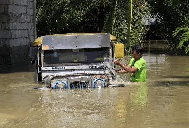 A resident splashes water on his vehicle while wading through floodwaters a week after typhoon Koppu battered Calumpit town, Bulacan province, north of Manila October 24, 2015. (Photo by Romeo Ranoco/Reuters)