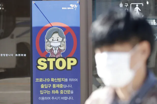 A man wearing a face mask walks past near a banner showing precaution against the coronavirus, at the Imjingak Pavilion in Paju, South Korea, Friday, October 23, 2020. South Korea recorded its highest increase in coronavirus cases in more than 40 days on Friday as more infections were reported at hospitals and nursing homes. (Photo by Lee Jin-man/AP Photo)
