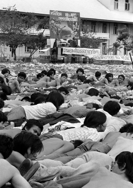 In this October 6, 1976 file photo leftist students who surrendered to police lie on the ground of the soccer field at Thammasat University in Bangkok, Thailand, awaiting orders from their captors. (Photo by Neal Ulevich/AP Photo)