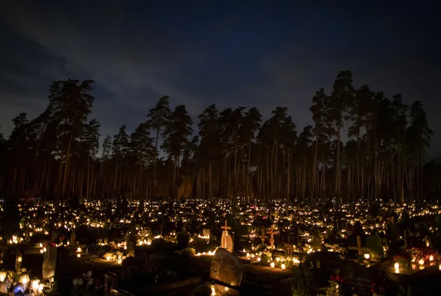 Relatives gather around some of the graves illuminated by candles during All Saints Day at the cemetery in Vilnius, Lithuania, Sunday, November 1, 2020. Candles illuminated tombstones in graveyards across Europe as people communed with the souls of the dead on Thursday, observing one of the most sacred days in the Catholic calendar. (Photo by Mindaugas Kulbis/AP Photo)