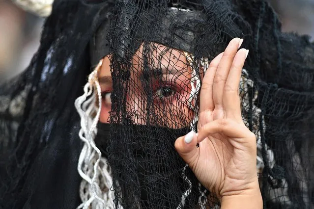 A woman gives the three-finger salute associated with pro-democracy protesters during an open-air art exhibition in Silom in Bangkok on October 29, 2020. (Photo by Mladen Antonov/AFP Photo)