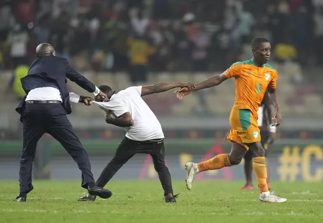 Ivory Coast's Max Gradel, right, is pulled by a fan who invaded the playing field at the end of the African Cup of Nations 2022 group E soccer match between Ivory Coast and Algeria at the Japoma Stadium in Douala, Cameroon, Thursday, January 20, 2022. (Photo by Themba Hadebe/AP Photo)