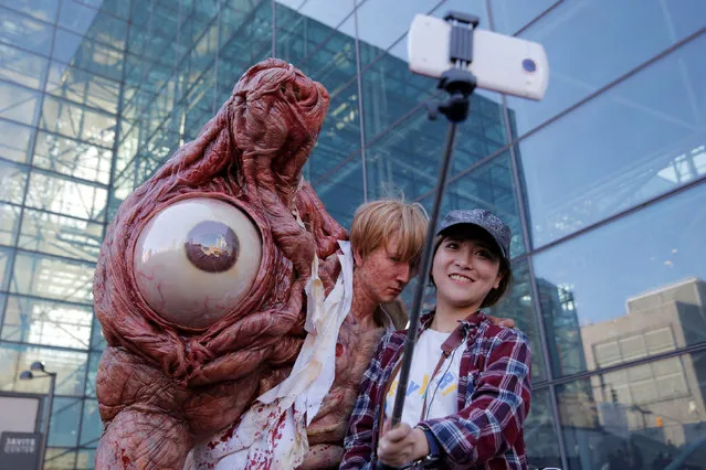 Chen Yifa from China poses for a selfie with a man dressed as William Birkin from Resident Evil at New York Comic Con in Manhattan, New York, U.S., October 7, 2016. (Photo by Andrew Kelly/Reuters)