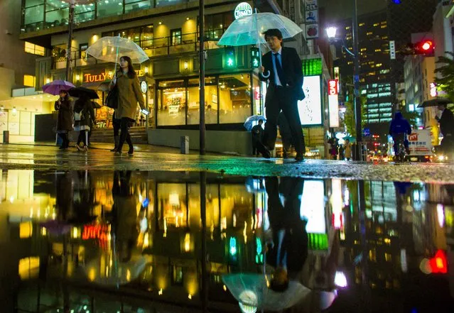 People cross a street in a business district on a rainy day in downtown Tokyo, November 25, 2014. (Photo by Thomas Peter/Reuters)