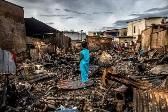 A boy stands in the remains of a burnt house in a residential area in Plumpang, north Jakarta on March 4, 2023, after a fire at a nearby state-run fuel storage depot run by energy firm Pertamina. (Photo by Aditya Aji/AFP Photo)