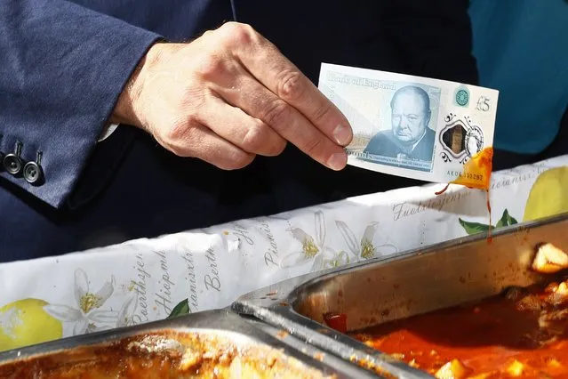 Bank of England governor Mark Carney tests a new polymer five pound note as he buys lunch at Whitecross Street Market in London, Britain September 13, 2016. (Photo by Stefan Wermuth/Reuters)