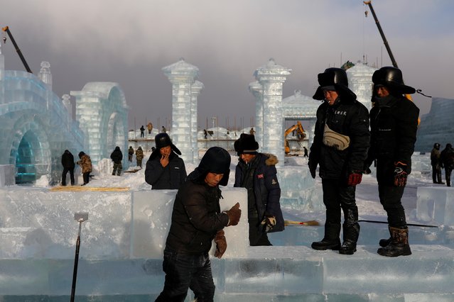 Workers smoke, while constructing ice structures at the site of the Harbin International Ice and Snow Festival before its opening in Harbin, China, December 18, 2020. (Photo by Carlos Garcia Rawlins/Reuters)