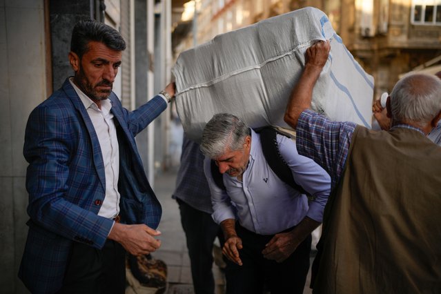 Porters place a load on a co-worker's back in the Eminonu commercial area of Istanbul, Turkey, Wednesday, September 24, 2025. (Photo by Emrah Gurel/AP Photo)