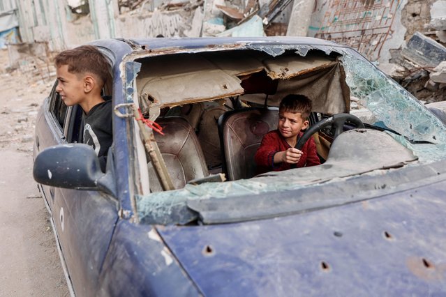 Displaced Palestinian children play in the wreckage of a car in the Tel al-Hawa neighborhood, in the southern part of Gaza City, on November 29, 2025. The health ministry in Hamas-run Gaza on November 29 said more than 70,000 people have been killed since the war between Israel and Hamas erupted more than two years ago. The milestone comes as a fragile US-brokered ceasefire largely holds, but with both sides accusing the other of violating the terms of the deal. (Photo by Omar Al-Qattaa/AFP Photo)