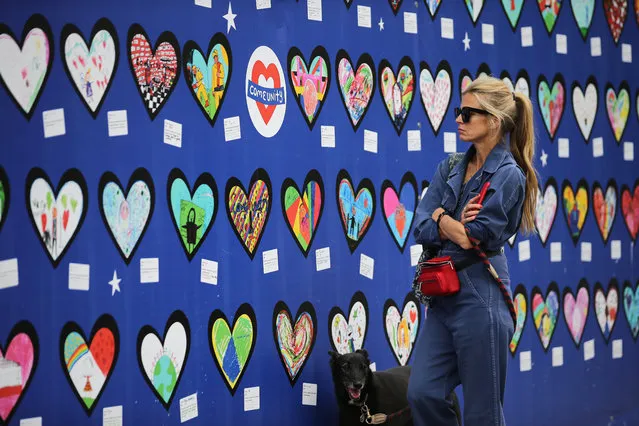 A woman looks at a wall of hearts with drawings and messages of support for the 71 people who died in the Grenfell fire, outside the Notting Hill Methodist Church in West London, on June 13, 2018. Commemorations begin on June 13, 2018, to honour the 71 people who died when a fire ripped through the Grenfell tower block in London one year ago. (Photo by Daniel Leal-Olivas/AFP Photo)