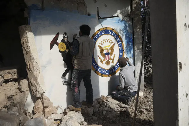 Syrian graffiti artist Aziz Al-Asmar, left, finishes work on his depiction of the events in Washington after the US president Donald Trump's supporters stormed the Capital, on a wall of a house destroyed in an airstrike, in Binish, Idlib province, Syria, Friday, January 8, 2020. (Photo by Ghaith Alsayed/AP Photo)