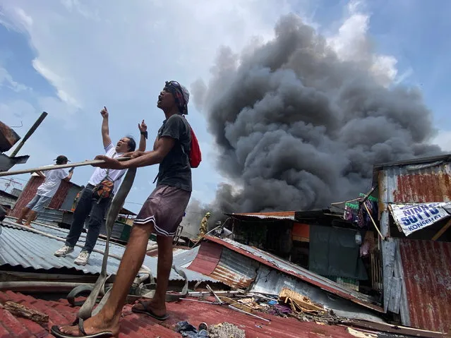 esidents shout for help next to burning shanties as a fire engulfs a slum area in Paranaque city, Metro Manila, Philippines, 18 May 2023. Authorities reported scores of fire fighters were injured when a fire truck overturned while responding to the site of the fire and dozens of families were rendered homeless. (Photo by Francis R. Malasig/EPA)