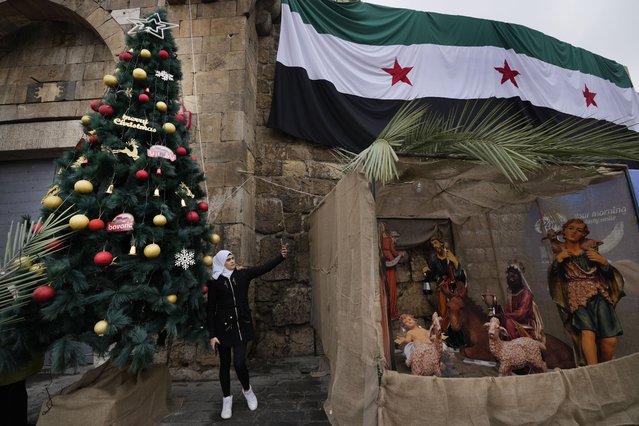 A Syrian Muslim woman takes a selfie in front of a Christmas tree in Bab Touma neighbourhood, in Damascus, Syria, Tuesday, December 24, 2024. (Photo by Hussein Malla/AP Photo)