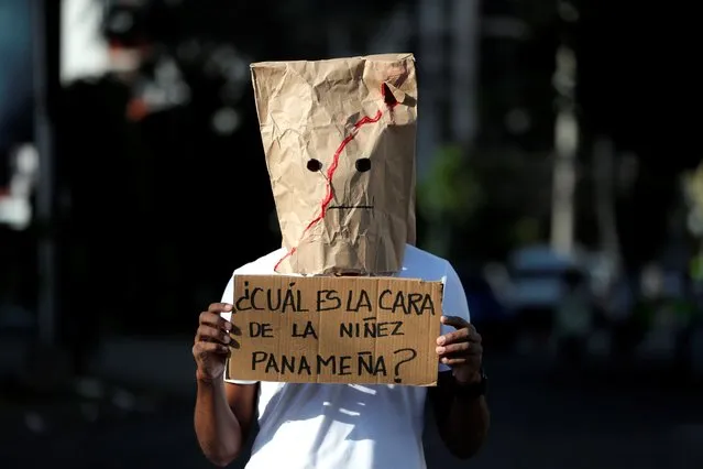 A person with the face covered shows a protest poster that reads: “What is the face of Panamanian children?”, during a new demonstration against child sexual abuse, in front of the headquarters of the National Secretariat for Children, Adolescents and the Family (Senniaf), in Panama City, Panama, 26 February 2021. Two weeks ago, a parliamentary subcommittee uncovered a scandal of sexual abuse and physical and psychological mistreatment of dozens of minors since 2015 in shelters under state supervision. The events have provoked a wave of social indignation for weeks with demonstrations throughout the country to demand justice. The scandal has led to Panama's attorney general Eduardo Ulloa's to announce his “irrevocable resignation” last Wednesday. (Photo by Bienvenido Velasco/EPA/EFE)