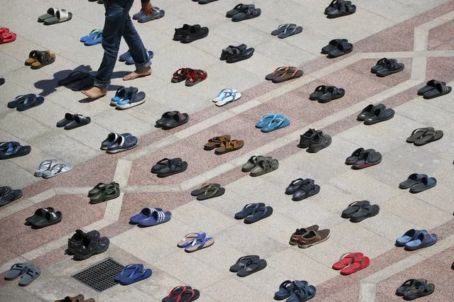 A man walks between slippers arranged in a spacing format as he attends Friday prayer at a mosque in Putrajaya, outside Kuala Lumpur, Malaysia, 05 February 2021. The Federal Territories Islamic Religious Department has approved a reduction of the number of congregation members allowed for Friday prayers and general mass prayers to half of the actual capacity of mosques, prayer halls and suraus with physical distancing of 1.5 metres effective based on the consent of Malaysian King Al-Sultan Abdullah Ri’ayatuddin Al-Mustafa Billah Shah applied to all Federal Territories, namely Kuala Lumpur, Putrajaya and Labuan. (Photo by Fazry Ismail/EPA/EFE)