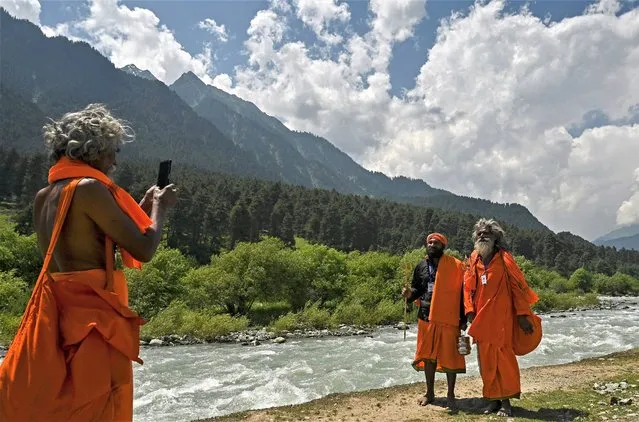 A Sadhu, or Hindu holy man, take pictures on a mobile phone at Nunwan Pahalgam base camp before proceeding towards the holy cave shrine of Amarnath on July 1, 2023. (Photo by Tauseef Mustafa/AFP Photo)