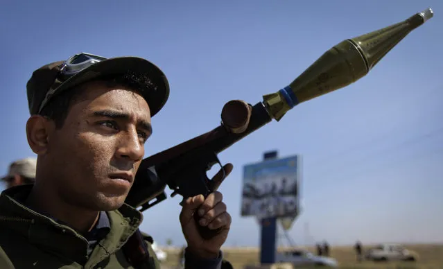 A rebel fighter holds a rocket propelled grenade launcher, near the front line in Brega, Libya Monday, April 4, 2011. (Photo by Ben Curtis/AP Photo)