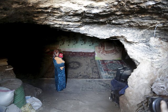 An internally displaced Syrian carries a baby inside her makeshift shelter that is an underground cave in Om al-Seer, southern Idlib countryside, Syria December 26, 2015. (Photo by Khalil Ashawi/Reuters)
