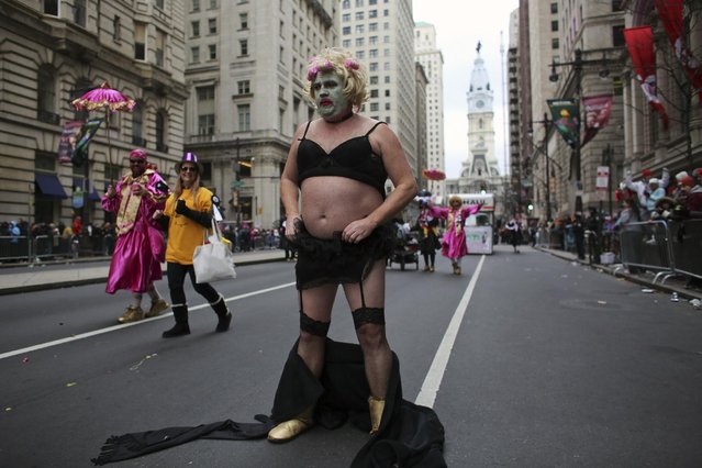 Comic club member Michael Kenney pauses on South Broad Street to adjust his costume during the 116th annual Mummers Parade in Philadelphia on Friday, January 1, 2016. (Photo by Joseph Kaczmarek/AP Photo)